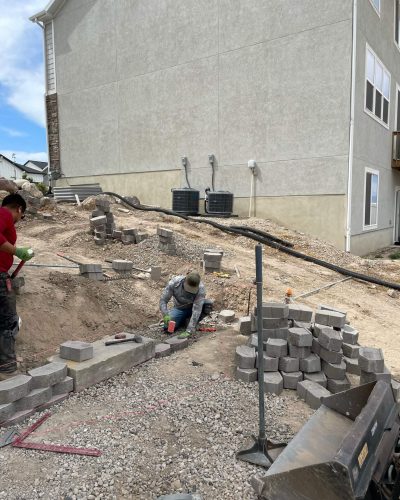 A worker installing blocks on the landscape on the front of the house.