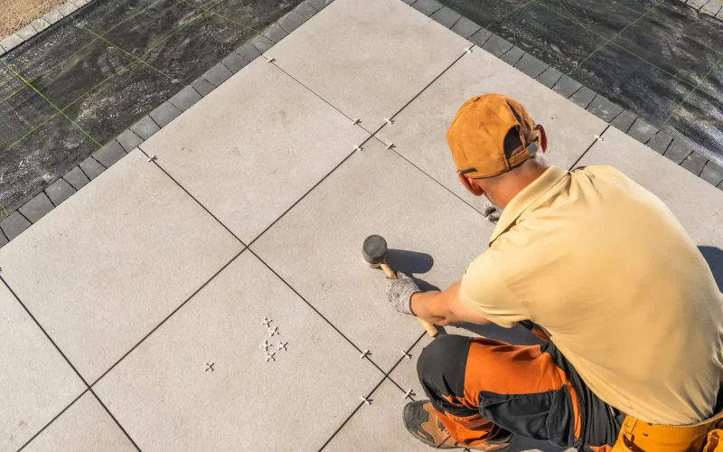 A man laying a tile for the garden patio floor.